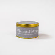 A Thousand Wishes soy wax candle in gold tin on white background, handpoured in India